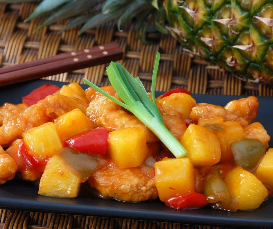 An inviting plate of Pineapple-infused Sweet and Sour Chicken, adorned with colorful bell peppers and succulent pineapple chunks.